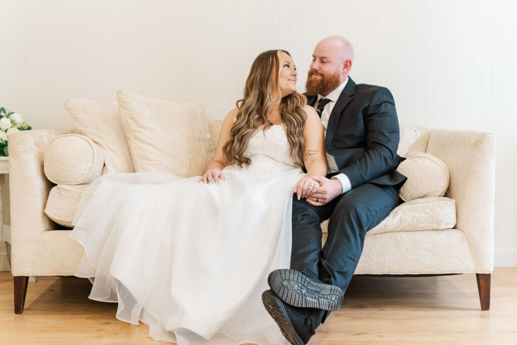 Bride and groom holding each other on a big cream colored couch