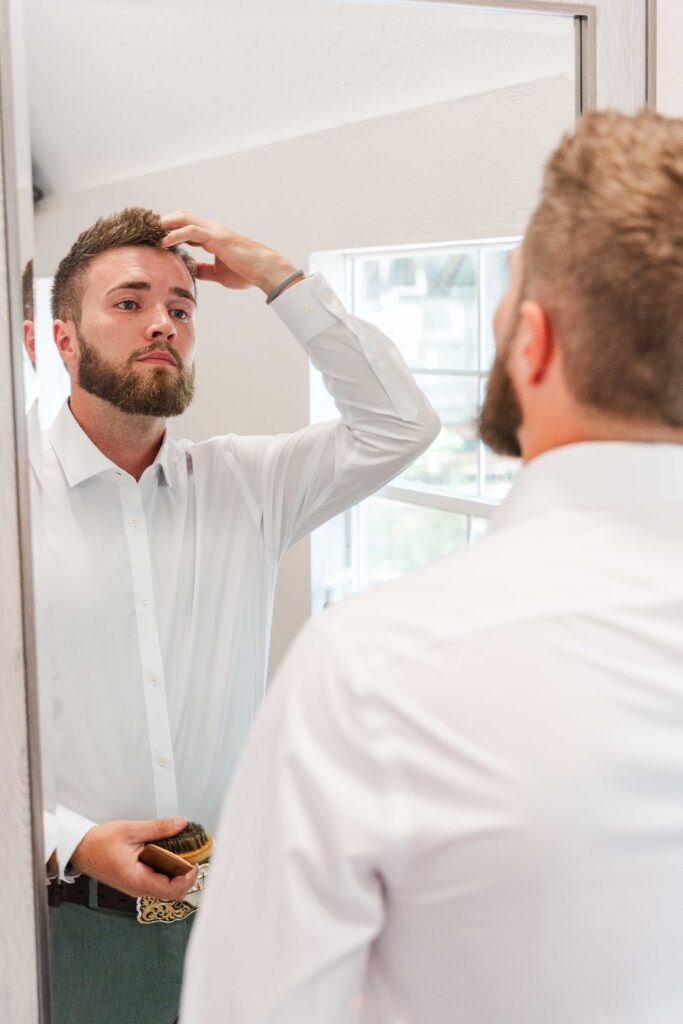 the groom looking at himself in the mirror