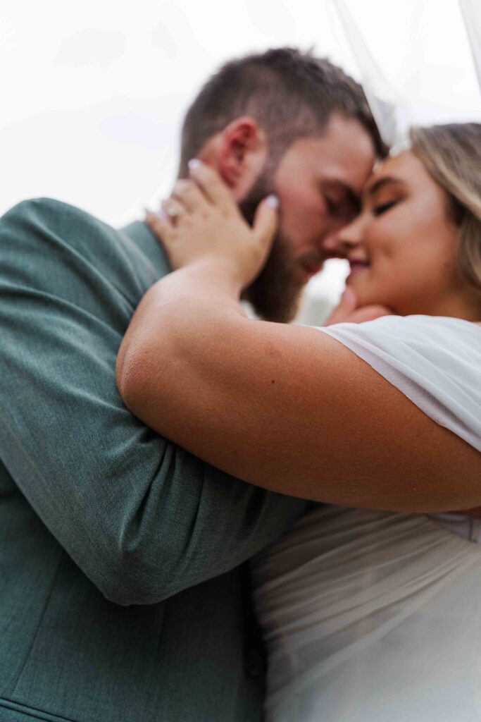 bride and groom cuddling just married with veil over them 