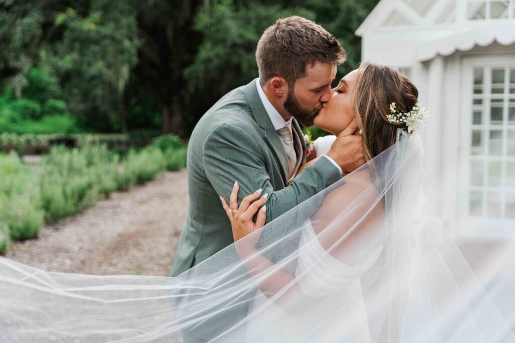 bride and groom cuddling just married with veil surrounding them 